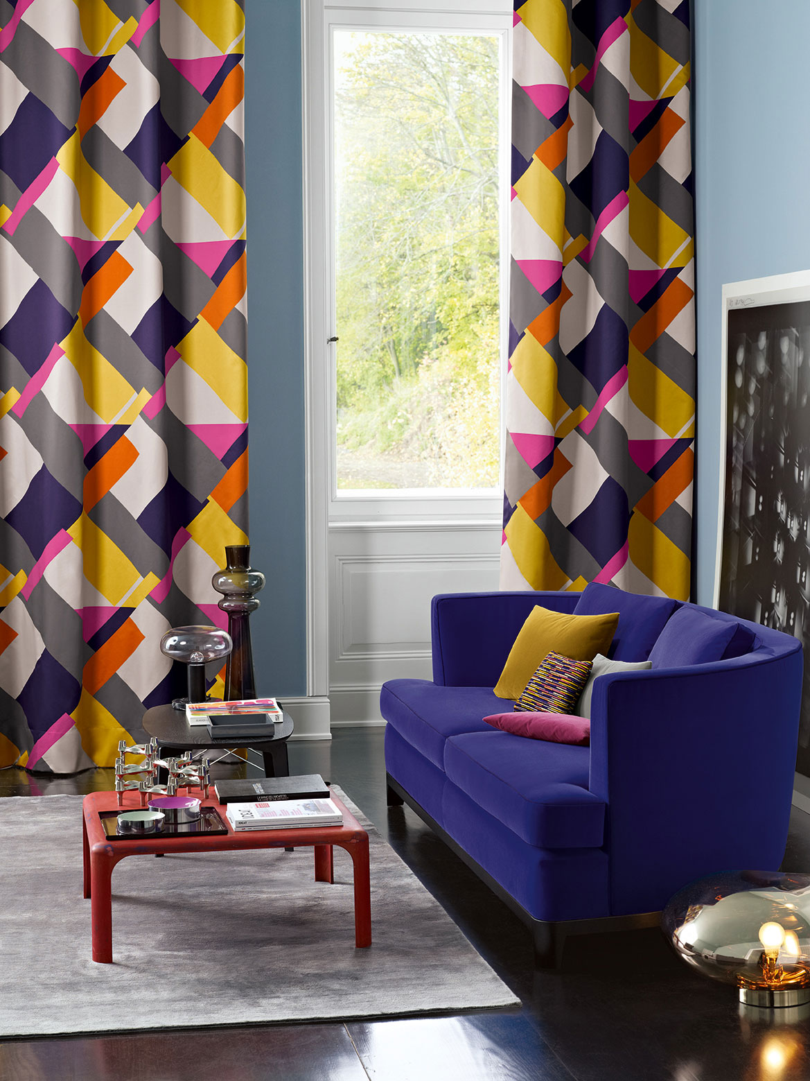 Farbenfrohe Gardinen mit grafischem Muster in einem Wohnzimmer mit blauem Sofa